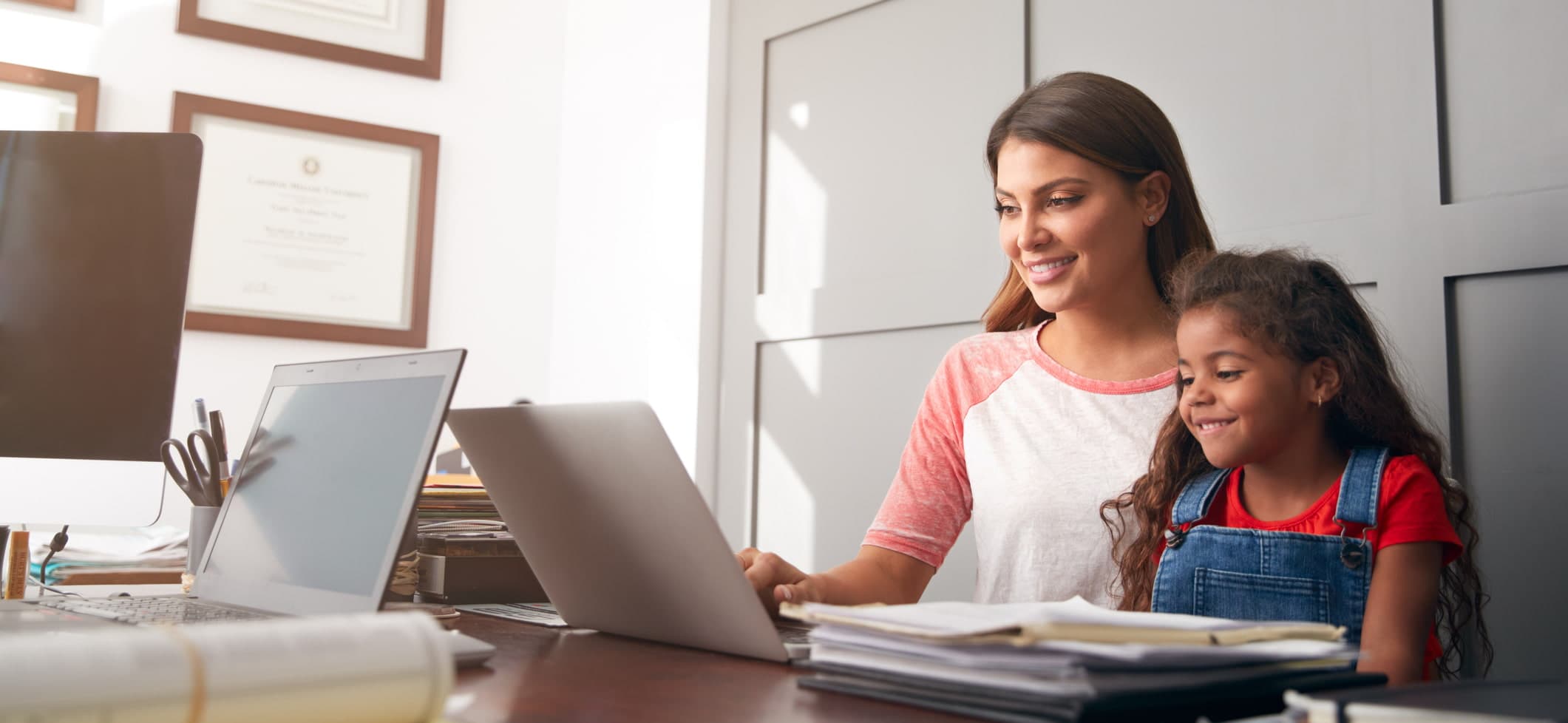 Hispanic Mother And Daughter Using Laptop In Home Office Together